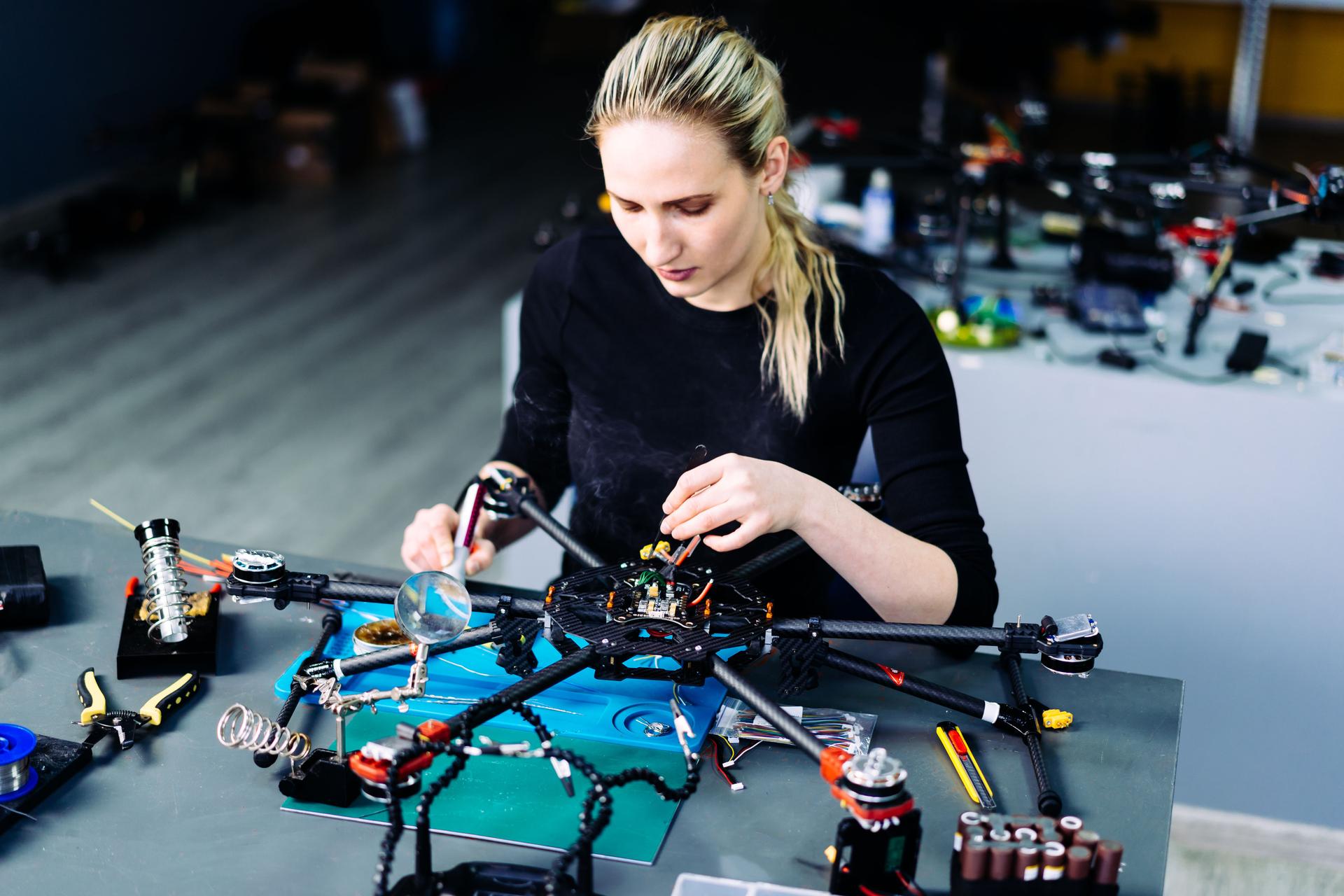 Engineer working on racing fpv drone combat kamikaze bomber in workshop.